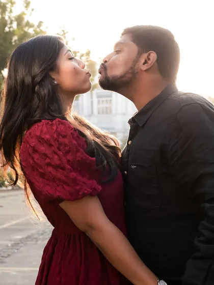 A playful and cute moment as the couple goes in for a kiss, captured in the warm light of the setting sun.