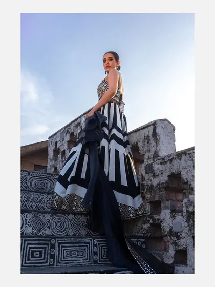 A powerful, low-angle shot of a model on a staircase, with her black and white lehenga flowing. This perspective creates a sense of grandeur and is perfect for high-fashion editorials.