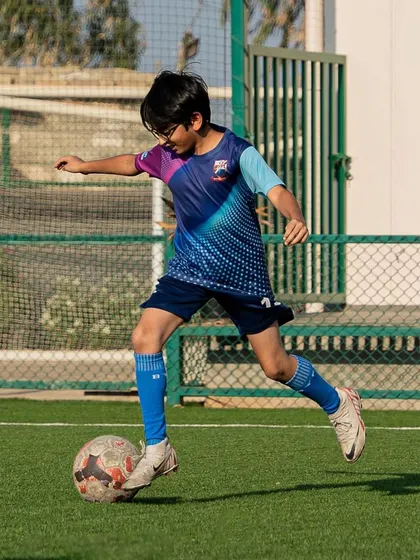 Our player Rian, happy and focused on the field, dribbling the ball with confidence.