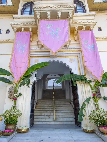 The entrance to the venue is marked with grand pink banners and banana leaf decorations, signaling a traditional and festive celebration.