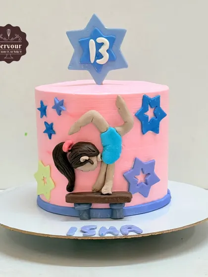 A gymnastics-themed cake for a 13th birthday. The pink cake is decorated with stars and a hand-molded fondant gymnast on a balance beam.