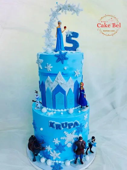 This two-tier Frozen cake brings the entire kingdom of Arendelle to the party. It features Elsa on top, with Anna, Kristoff, Sven, and Olaf around the base, all set against an icy blue castle design.