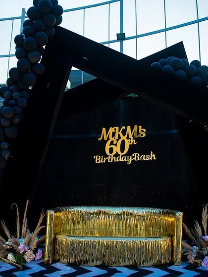 A close-up of the custom-built stage for the 60th birthday party, highlighting the gold lettering and fringe sofa.