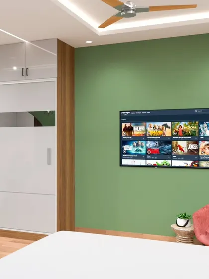 This angle focuses on the sliding wardrobe in a glossy grey finish with a wooden accent strip. The wall-mounted TV on the green accent wall is perfectly positioned for viewing from the bed.