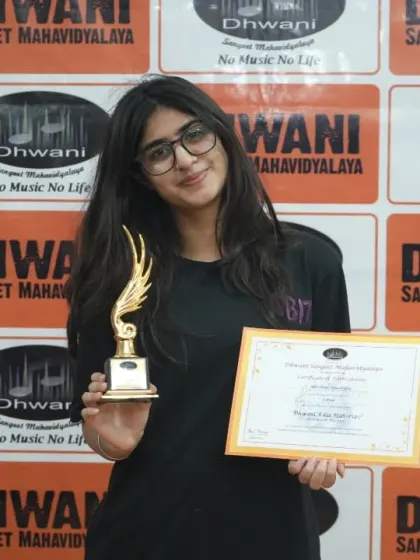 A young woman proudly holds her certificate and trophy.