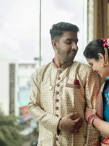 A quiet moment between Padmashree and Nikil during their engagement ceremony, captured against a window with soft natural light.