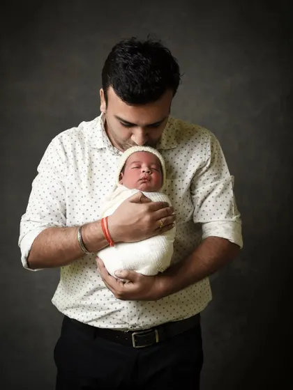 A father's pride and joy. This classic studio portrait shows a dad holding his newborn close, a simple and powerful image of their connection.