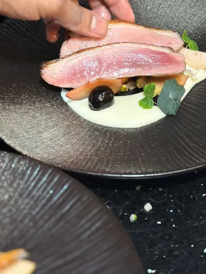 Placing slices of perfectly pink duck breast onto the plate. This action shot shows the final assembly of my Magret of Duck dish.