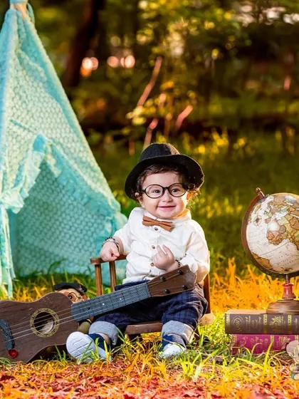 A little scholar sits in a field with a globe, books, and a guitar. This outdoor themed shoot is perfect for capturing a child's curious and adventurous spirit.