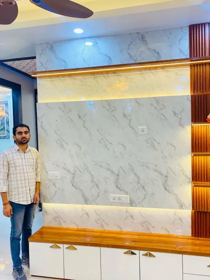 Another shot of me with the completed TV unit, showing how all the elements like the false ceiling, lighting, and furniture come together.