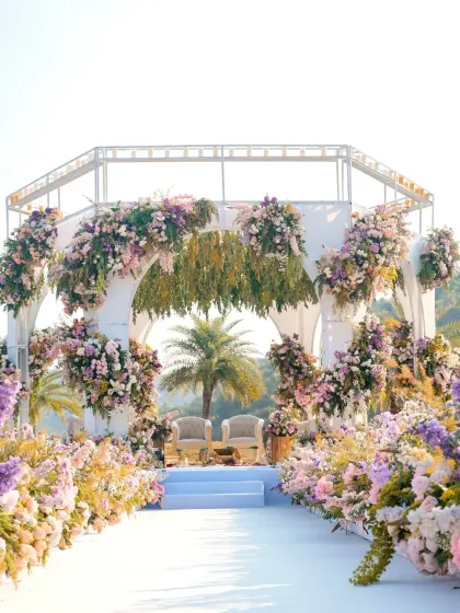 A full view of the stunning mandap at the Mementos by ITC Hotels in Udaipur. The aisle is lined with a meadow of pastel flowers, creating a pathway that feels like walking through a dream.