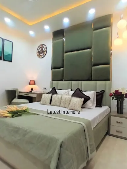 A beautiful bedroom with a symphony of green colors and comforting textures. The dark green geometric headboard is the star of the room, complemented by a lighter green bed and bedding.