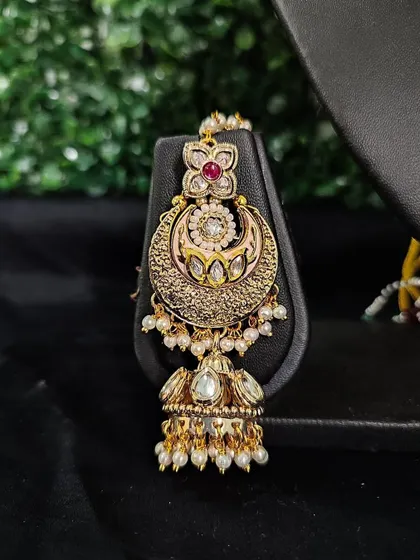 A unique crescent-shaped earring with delicate engraving and a small jhumka drop. This rental piece is perfect for a subtle yet elegant look.