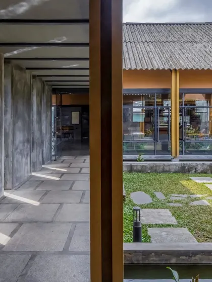 The building's structure is framed with ISMB sections, allowing for large, open spaces and expansive views of the courtyard and landscape. The walls are made of ferrocement finished with microconcrete.