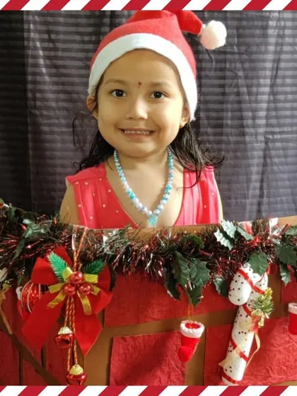 A smiling child in a Santa hat poses in our Christmas sleigh prop.
