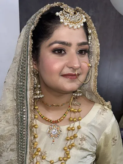 A detailed close-up of our elegant bridal makeup. This look features soft, blended eyeshadow, precise eyeliner, and a natural blush, all designed to enhance her features while complementing the intricate gold jewelry and attire.