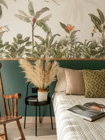 The guest room has a tropical getaway theme, with a vibrant botanical wallpaper and a vintage rocking chair.