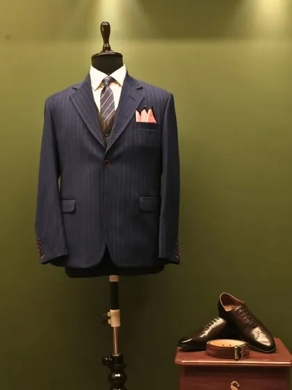 This is the same timeless navy pinstripe suit, presented here as a still image. It allows for a longer look at the harmony between the suit, the vest, the striped tie, and the contrasting pocket square, a complete sartorial statement.