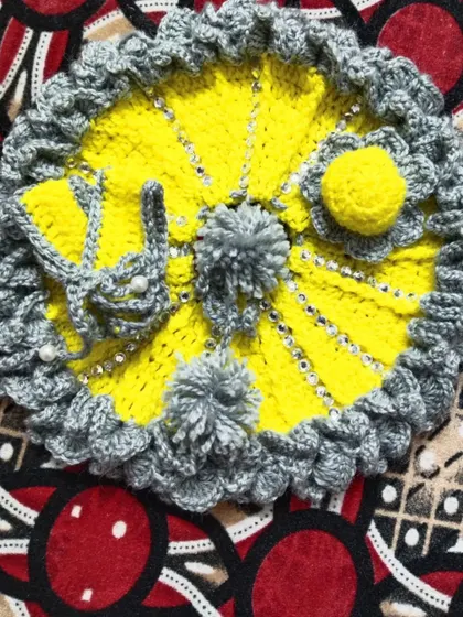A cheerful yellow and grey winter set. This woolen dress is decorated with grey pom-poms and comes with a matching crochet bag for Kanha Ji's essentials.