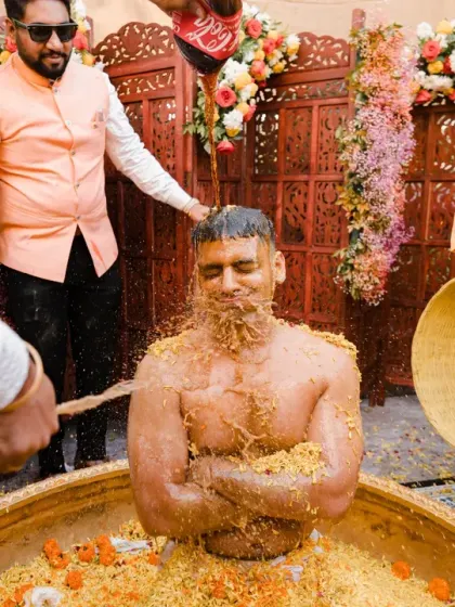 The groom gets the ultimate haldi treatment, being drenched in a tub of flowers and turmeric-colored water. This is the grand finale of a truly epic haldi celebration.