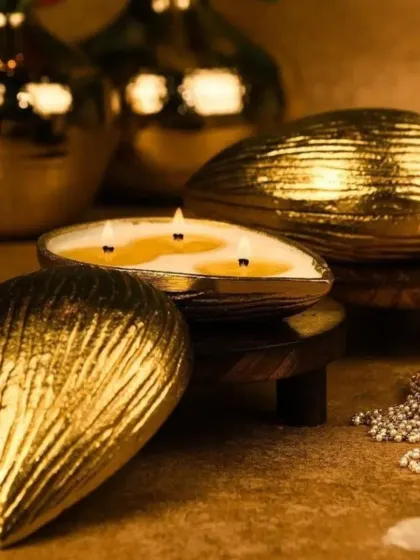 This is my almond-shaped urli candle, crafted from aluminum with a golden finish. When lit, the three wicks create a warm glow that highlights the intricate texture of the container.