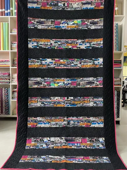 A "Graffiti" quilt with strips of colorful, text-based fabric separated by black bars, creating an urban, modern look.