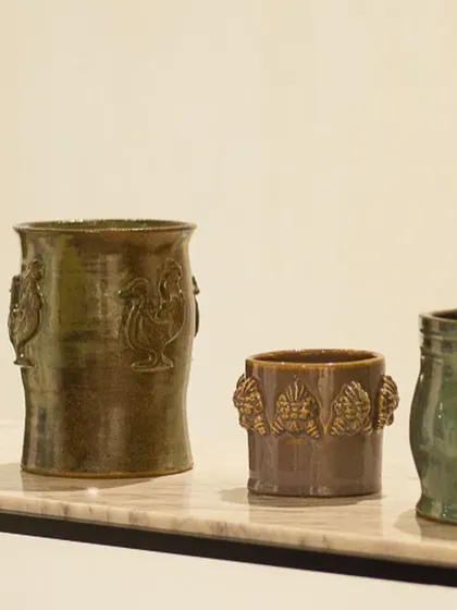 A collection of rustic planters featuring detailed sprig work. The rooster and leaf motifs are pressed from molds and applied by hand, giving these pots a classic, handcrafted feel.