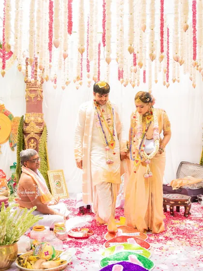 A South Indian couple during their wedding ceremony under a canopy of traditional flower strings.