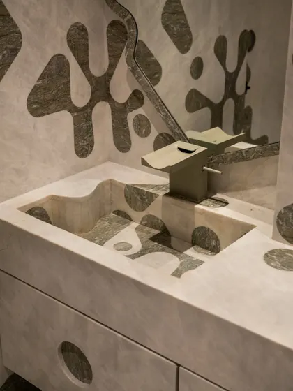 A close-up of the sculptural, integrated sink, where the inlay pattern continues seamlessly from the vertical wall onto the horizontal surface and into the basin itself.