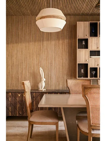 A closer look at the wood-clad dining room, focusing on the custom display cabinet and the elegant white pendant light.