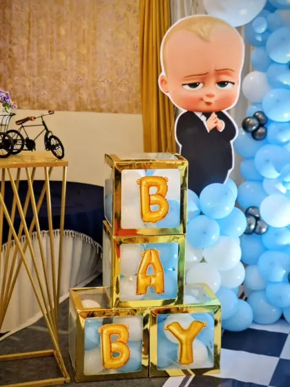 Fun props from the Boss Baby party, including a character cutout, 'BABY' blocks with gold balloon letters, and a decorative miniature bicycle.