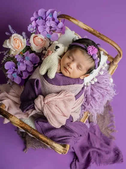 A floral haven for the tiniest treasure. This dreamy setup uses shades of lavender and pink, with a miniature bed and soft wraps to create a magical, fairytale-like portrait.