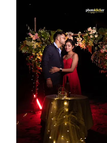A tender moment as the groom kisses the bride's forehead during their romantic dinner setup on the beach, surrounded by fairy lights.