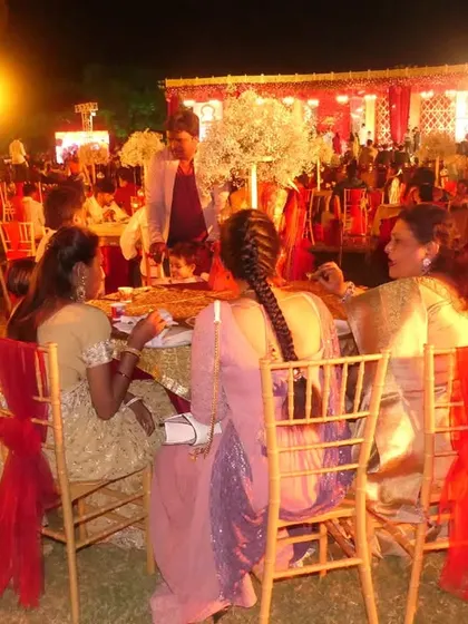Guests enjoying their meal at an outdoor royal wedding reception. The warm lighting and elegant seating create a magical atmosphere for the celebration.
