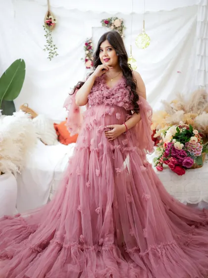 Blooming with love. This mama-to-be is surrounded by flowers in a romantic, boho-inspired setting, wearing a stunning pink floral-detailed gown.