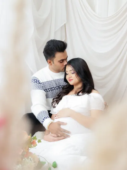 A soft and dreamy couple's portrait in all white. The gentle light and tender pose create a feeling of peace and serenity as they await their baby.