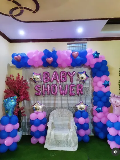 A full view of the pink and blue baby shower setup. The decor includes balloon pillars with foot-shaped foil balloons, adding a cute touch to the theme.