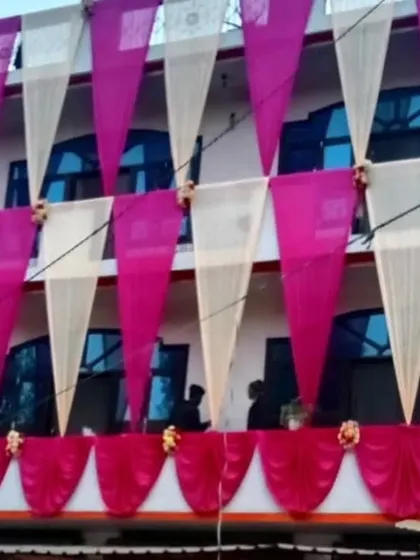 A house facade at night decorated with vertical drapes in off-white and pink, creating an elegant and festive look.