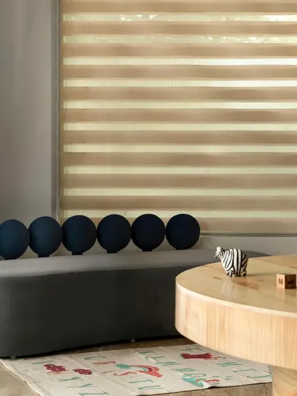 A serene waiting area with a curved grey bench and spherical cushions. The space is designed to be calming for parents, with soft, ambient light filtering through the blinds and a minimalist aesthetic.