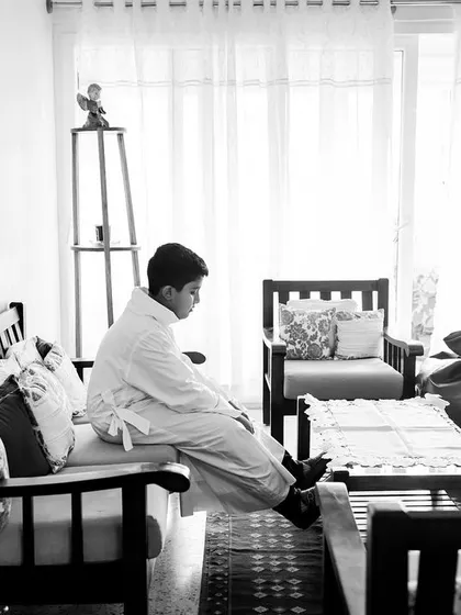 A candid, pensive moment of a boy sitting on the sofa during his Holy Communion day. Black and white photography can add a sense of quiet importance and reflection to event photos.
