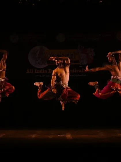 My dancers frozen in a gravity-defying leap during a Chhau performance. The dark stage and dramatic lighting focus entirely on the athleticism and power of the performers.