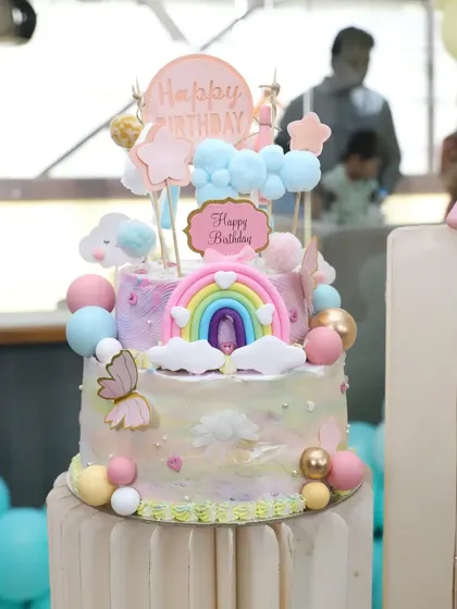 A beautiful pastel rainbow cake with a butterfly and cloud theme, perfect for a whimsical party.