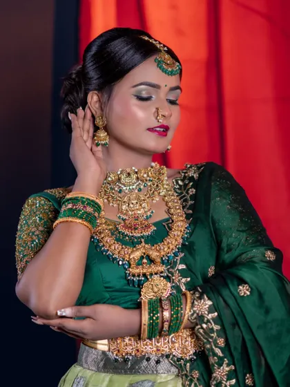 A close-up with eyes closed, focusing on the makeup and the heavy, ornate temple jewellery set.