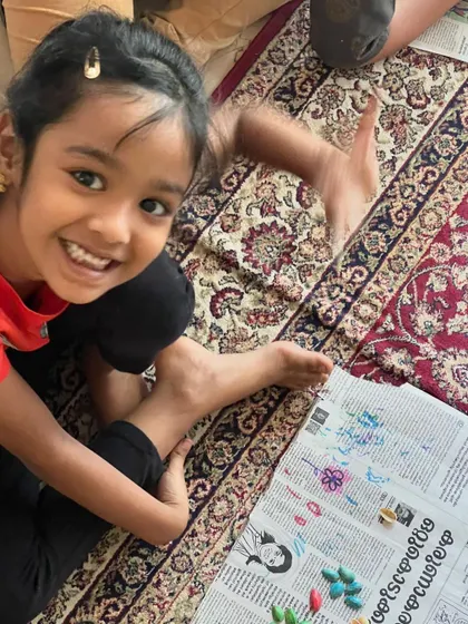 Such a bright, happy smile from this little artist. She is so proud of the colorful flower she created using painted pistachio shells.