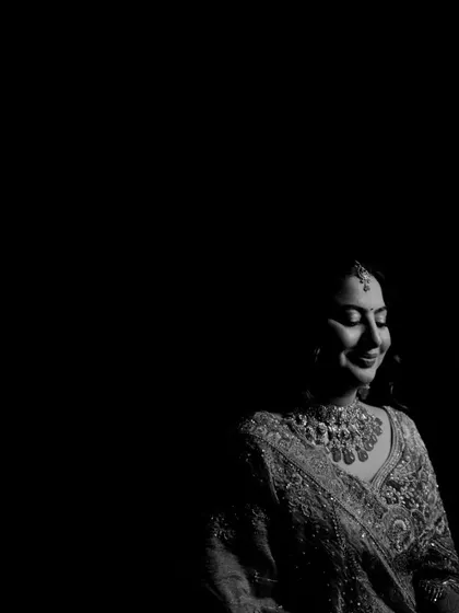 A dramatic black and white bridal portrait using shadow to create a moody and artistic effect, highlighting the bride's serene smile.
