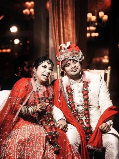 A candid moment of shared laughter during the wedding reception. The couple is watching their pre-wedding video on screen, and their genuine reaction makes for a heartwarming and memorable photograph.