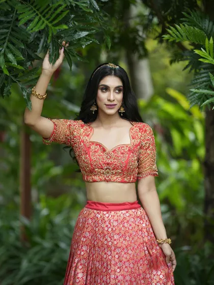 Another angle of the coral-red half saree, highlighting the beautiful craftsmanship and the way the outfit moves.