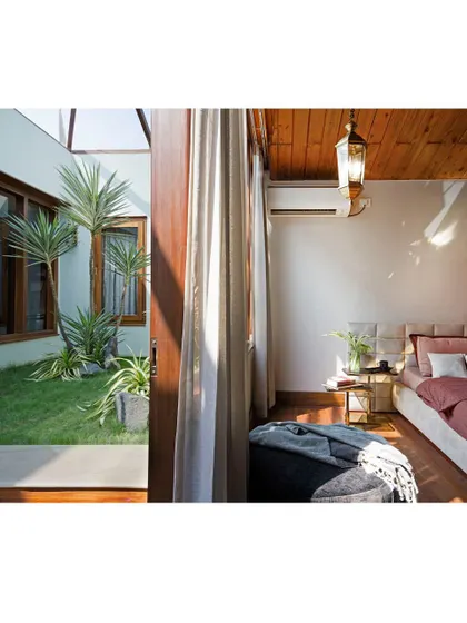 Sunlight streams into the master bedroom, highlighting the seamless transition to the outdoor courtyard. This design choice ensures the residents wake up with nature, promoting a sense of peace and well-being.
