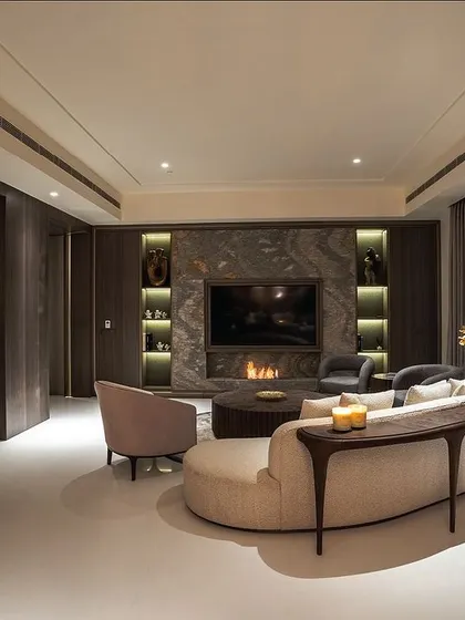 A cozy lounge area featuring a curved sofa and a custom console table, perfect for intimate conversations. The integrated fireplace and warm lighting enhance the inviting atmosphere.