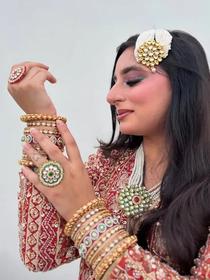 Details of a heavily accessorized party look. The makeup is kept glamorous with a focus on the eyes to balance the statement jewelry.